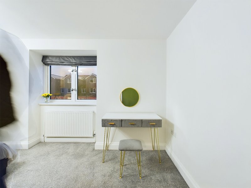 Modern bedroom with desk, chair, window and green circular wall decoration