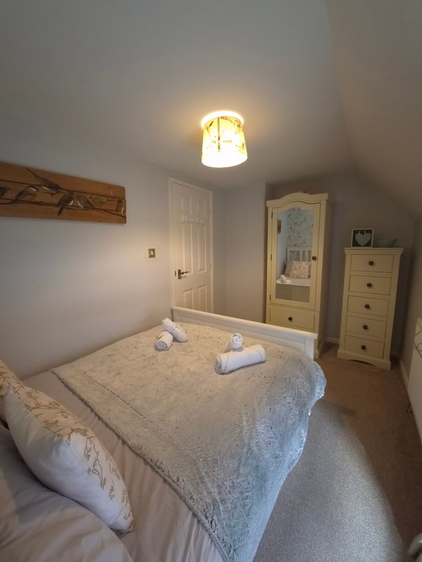 Bedroom with double bed, wooden furniture, ceiling light, and two doors