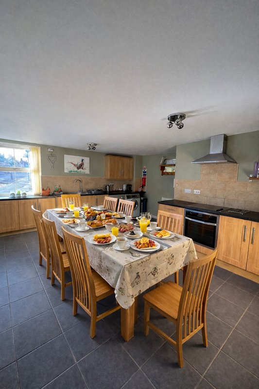 Open-plan kitchen and dining area with wooden furniture, set table with food and drinks