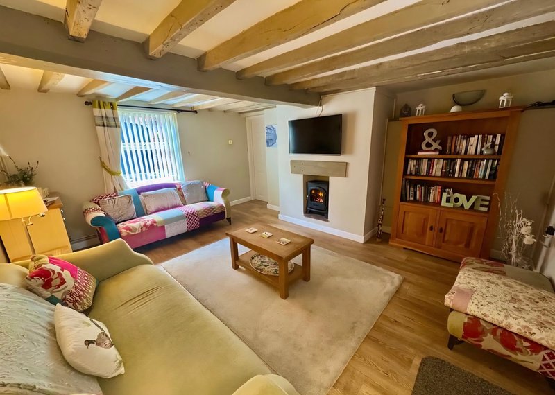 Spacious living room with wooden beams, colorful sofas, fireplace, bookshelf and wood furniture