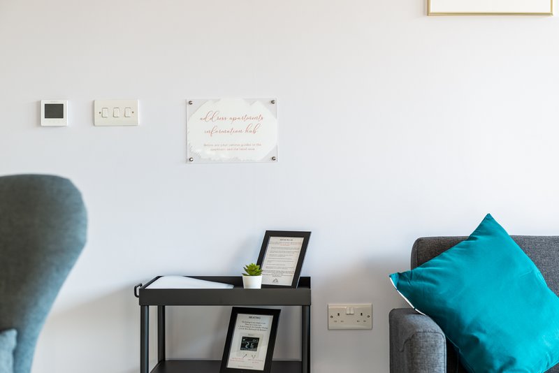 Modern living room with gray sofa, turquoise cushion, black side table and wall decor