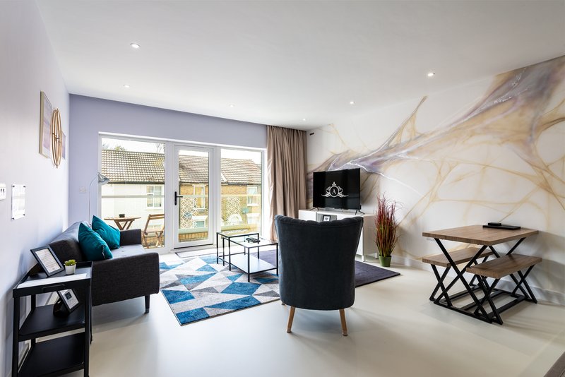 Modern living room with black sofa, blue accent chair, marble feature wall and patio doors