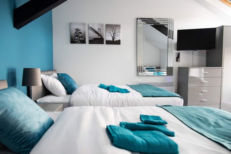 Modern bedroom with twin beds, turquoise accents, wall art, and mirrored wardrobe