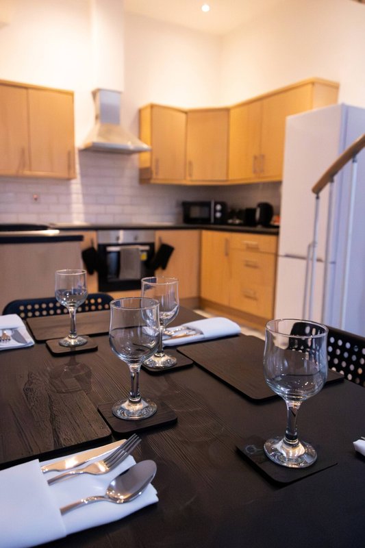 Kitchen dining area with wooden cabinets, set table with glasses and place settings