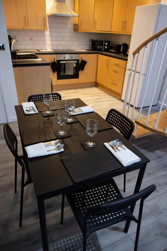 Kitchen and dining area with yellow cabinets, black dining table, and place settings