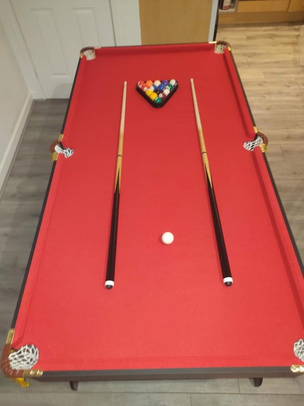 Red pool table with balls and cues in recreational room
