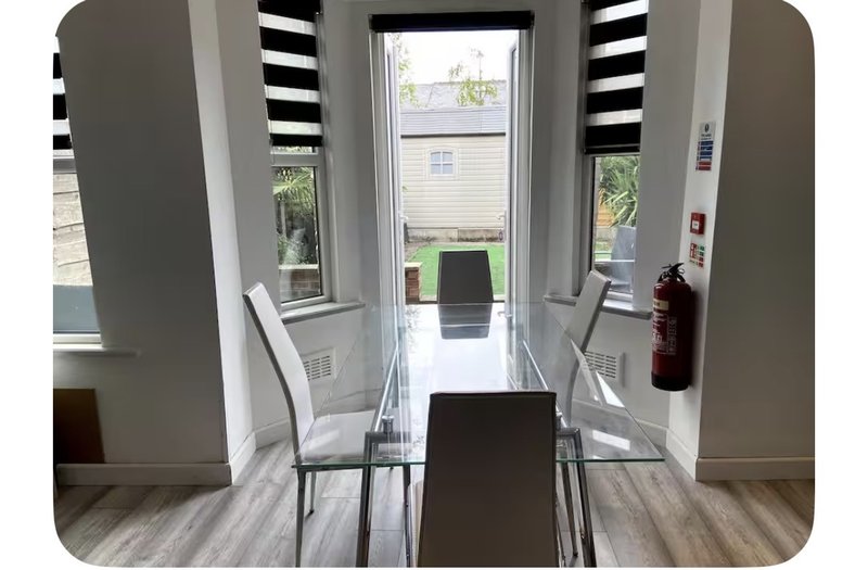 Bright hallway with striped roman blinds, glass door, wooden flooring and modern seating