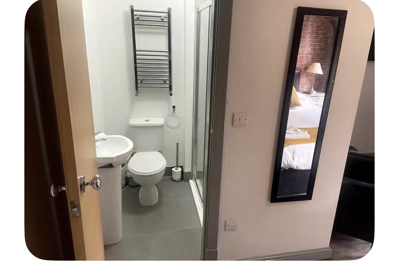 Compact bathroom with toilet, sink, towel rail and mirror on pink wall