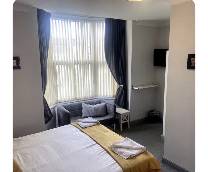 Modern bedroom with double bed, window seat area, blue curtains and seating nook