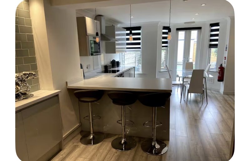 Modern open-plan kitchen and dining area with white cabinetry, island seating, and wooden flooring
