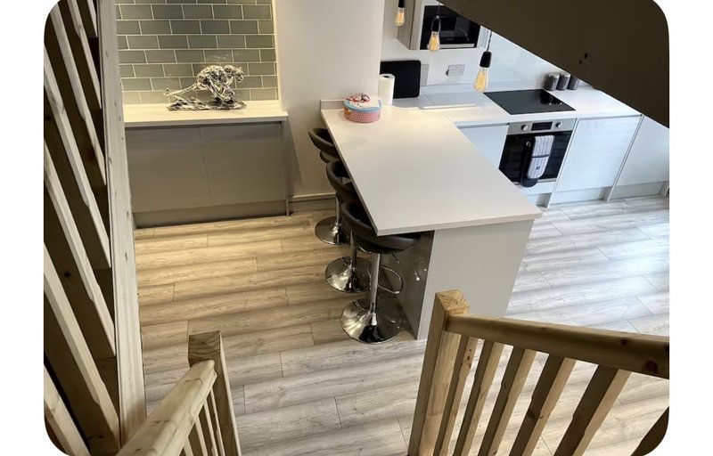 Modern kitchen with white counters, wooden flooring, subway tile splashback and bar seating