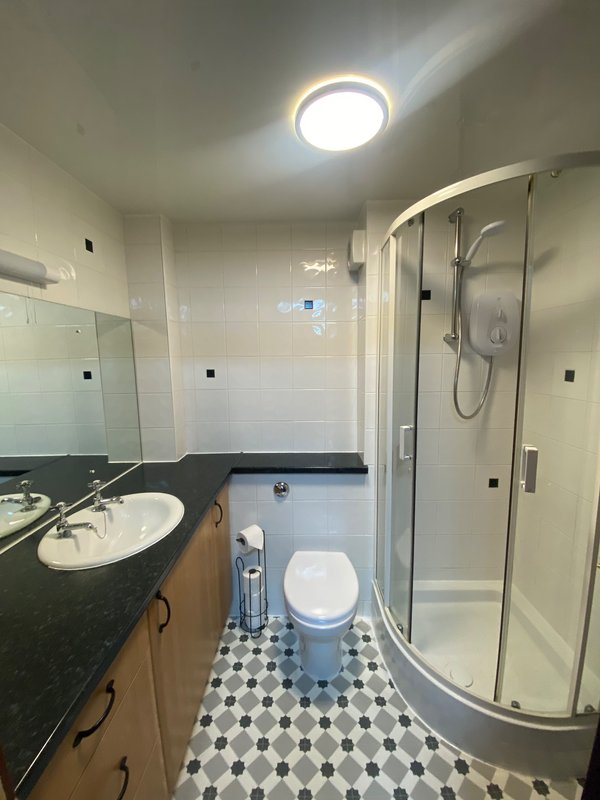 Modern bathroom with vanity sink, toilet, shower enclosure and geometric tile floor