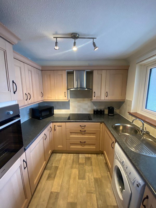 Modern kitchen with wooden cabinets, stainless steel appliances, and wooden flooring