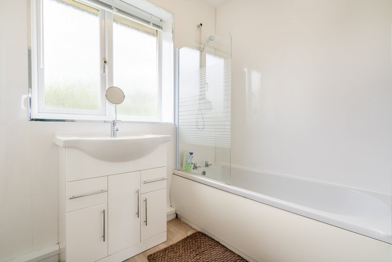 Modern bathroom with white vanity, sink, bathtub, shower screen and window