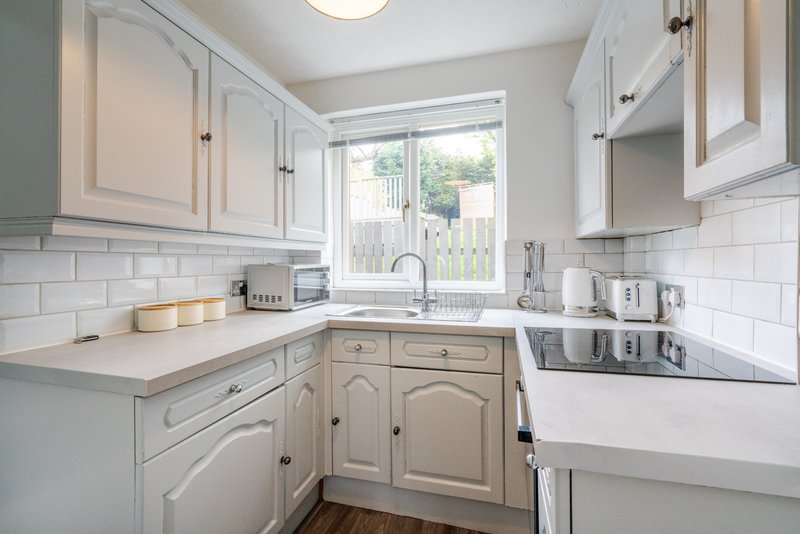 Bright modern kitchen with white cabinetry, subway tile backsplash, and window overlooking garden