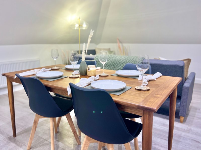 Dining room with wooden table, navy chairs, place settings, glasses and table decor