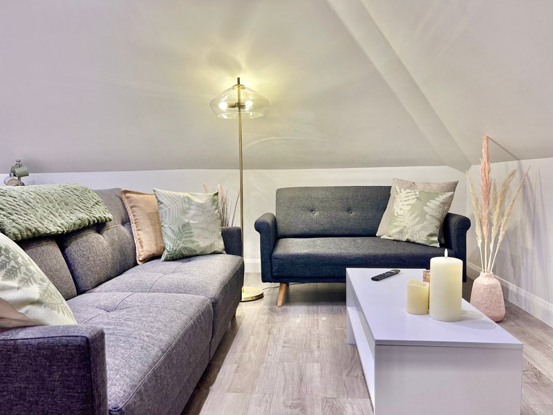 Attic living room with two sofas, floor lamp, white coffee table and decorative cushions