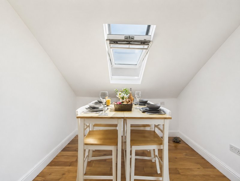 Compact dining area with wooden table, two chairs, skylight, and hardwood flooring