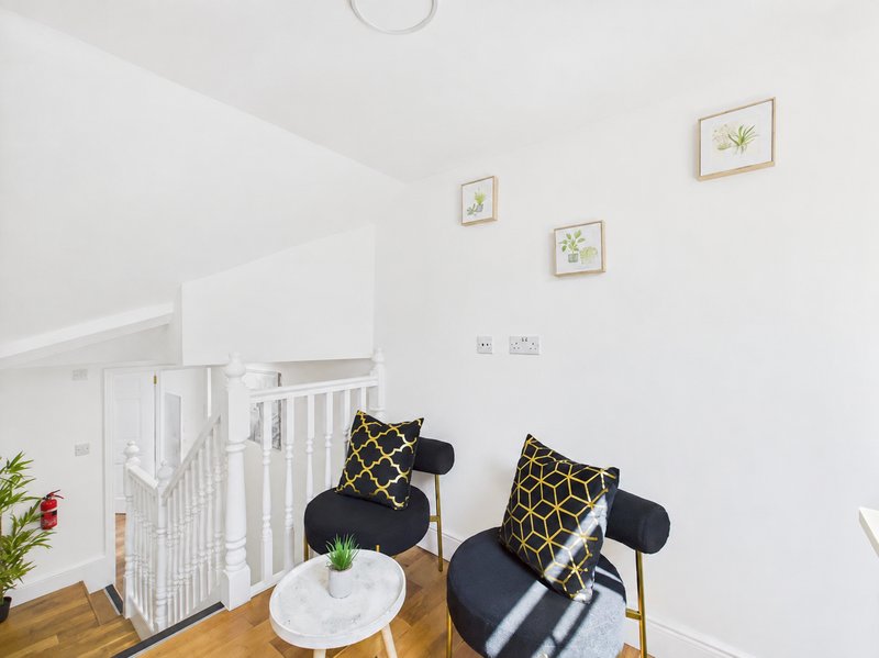 Bright nursery room with white crib, black chairs with patterned cushions, and wall art