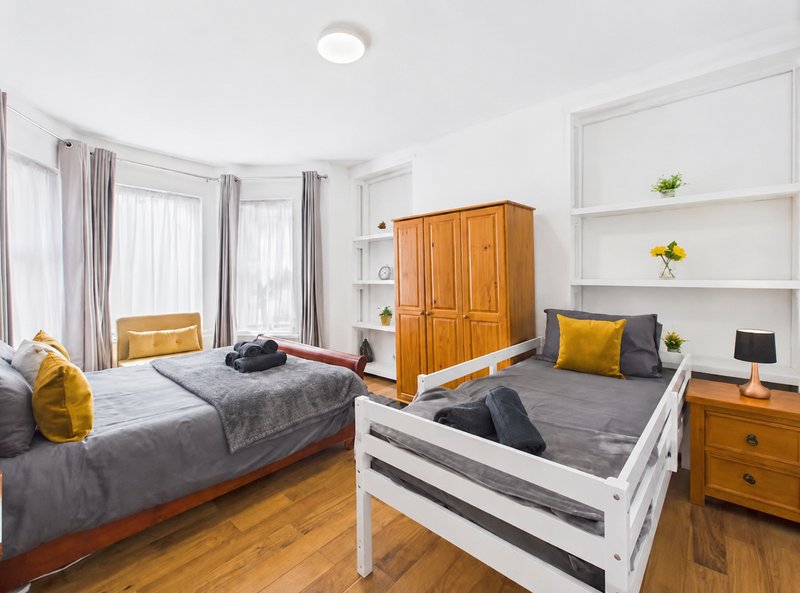 Bright bedroom with two beds, wooden furniture, yellow accents, and built-in shelving