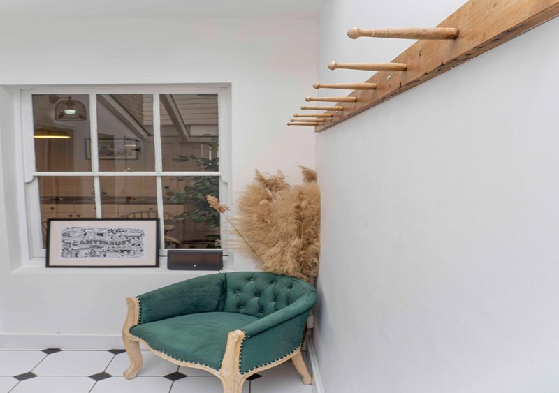 Modern entryway with green upholstered bench, pampas grass, wooden beams and large window