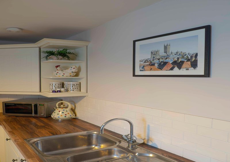 Kitchen with wooden countertop, stainless steel sink, white subway tile backsplash and framed artwork