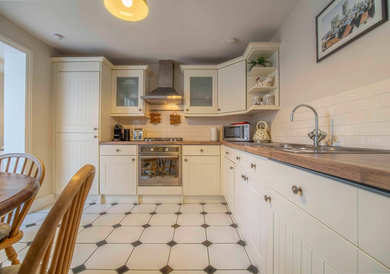 Cream and wood kitchen with white cabinetry, tiled floor, and dining chairs