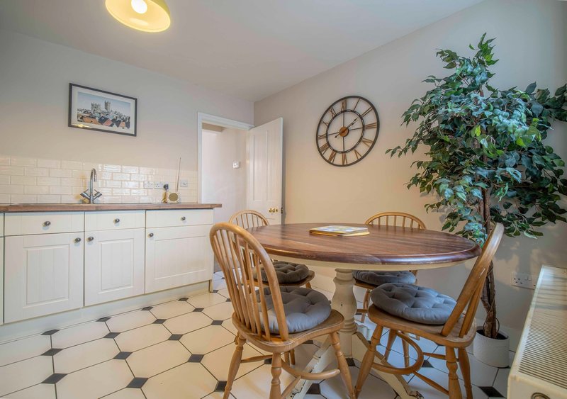 Kitchen-dining area with white cabinetry, wooden table, chairs, and potted plant