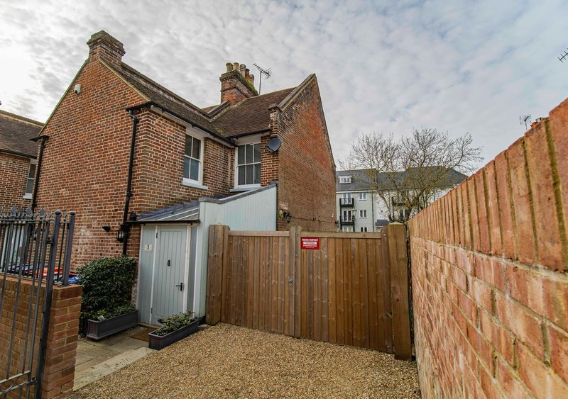 Red brick Victorian terrace house with wooden gate, gravel driveway and side garden