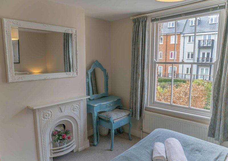 Bedroom with fireplace, blue chair, double bed and large window overlooking street