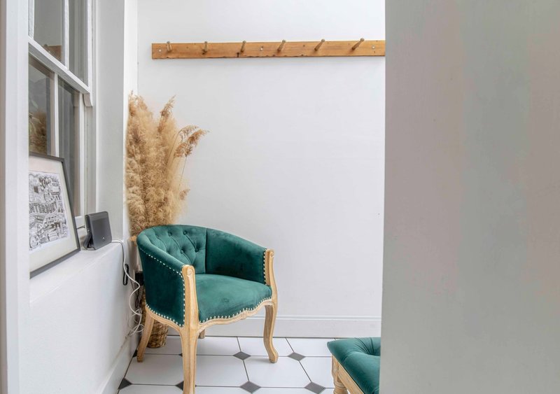 Modern corner seating area with teal upholstered chair, pampas grass, and wooden wall shelf