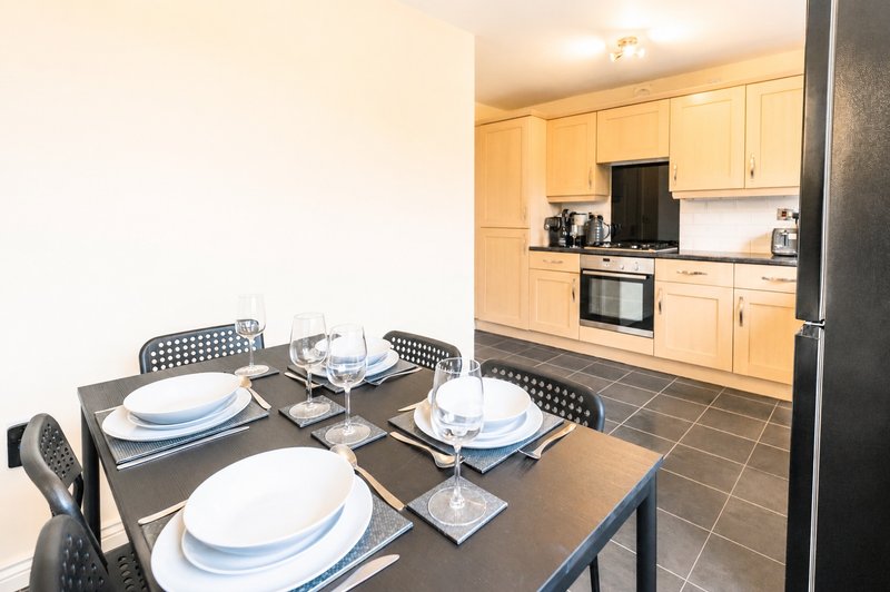 Modern, fully equipped kitchen and dining area with everything you need for a comfortable stay. Features a full-size fridge freezer, oven, hob, microwave, dishwasher, and dining table seating.
