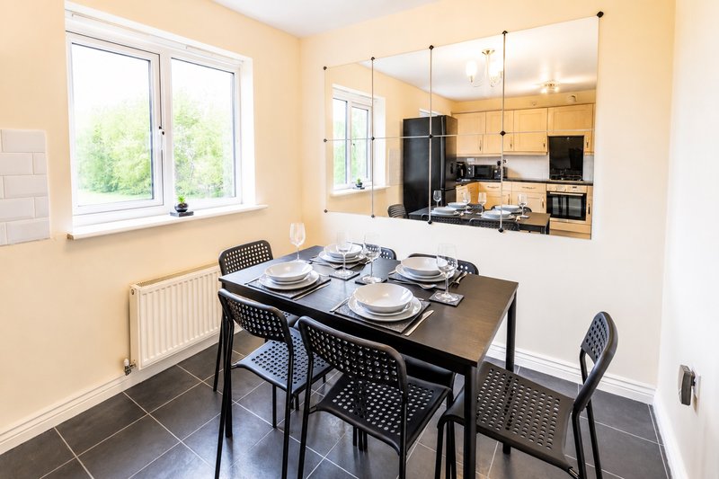 Open-plan dining and kitchen area with black table, chairs, and modern appliances