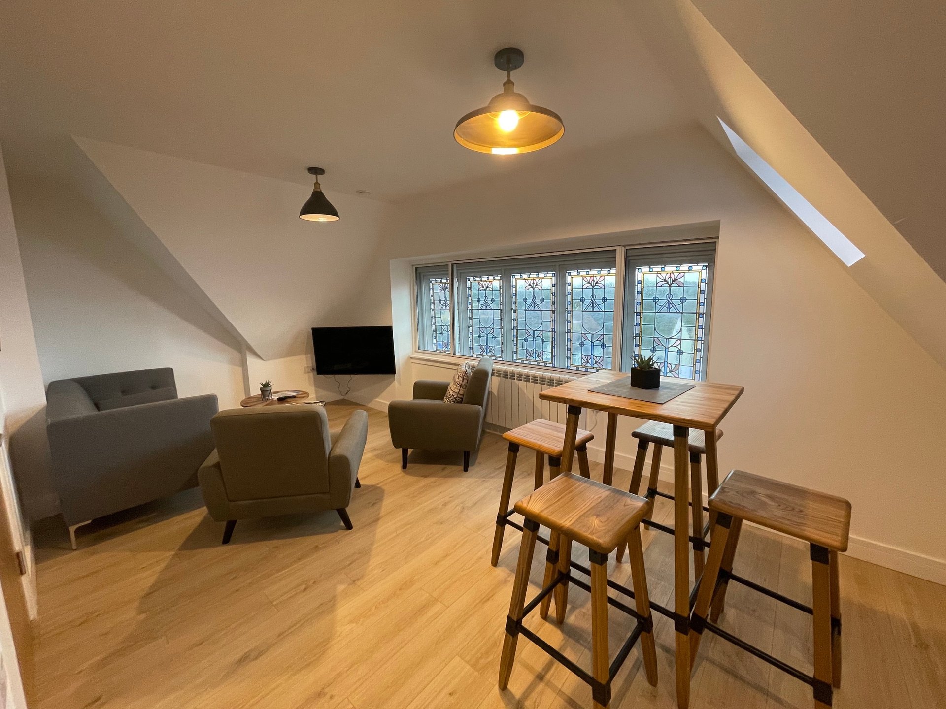 Bright attic apartment with wooden floor, seating area, dining table and large windows