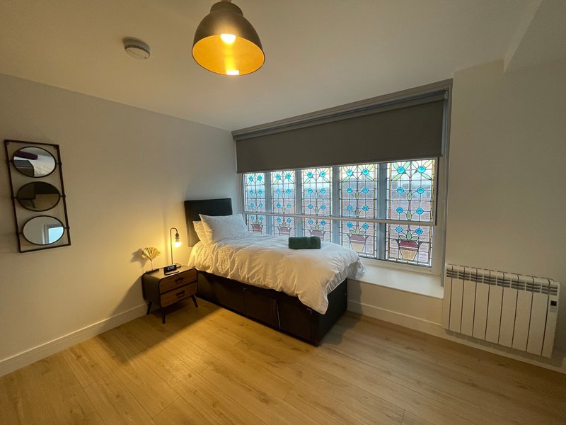 Bright bedroom with single bed, wooden floor, pendant lamp and large window