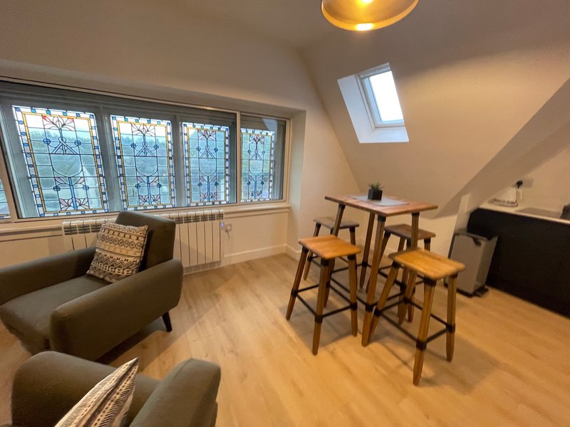 Modern attic room with seating area, dining table, wooden flooring and skylights
