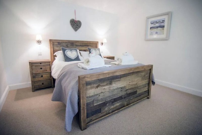 Bedroom with wooden bed frame, bedside table, white linens and heart decoration