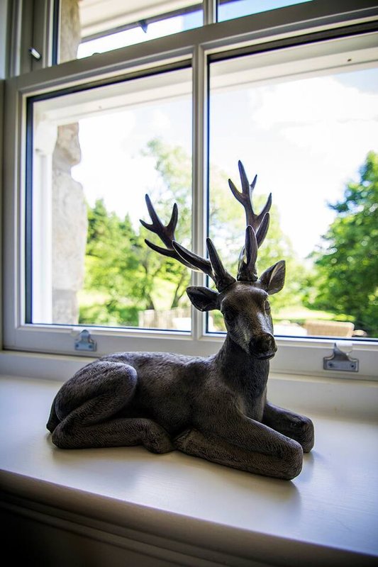 Windowsill with decorative black deer statue and garden view through double windows