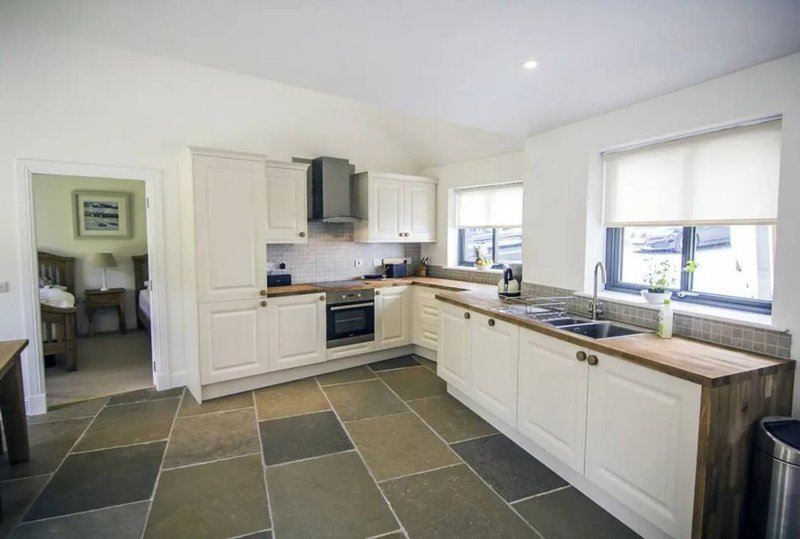 Modern kitchen with cream cabinets, slate flooring, wooden countertop and window views