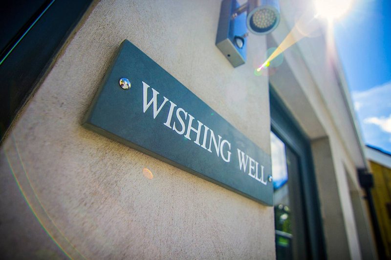 Exterior entrance with dark green nameplate reading 'Wishing Well' on cream-colored wall