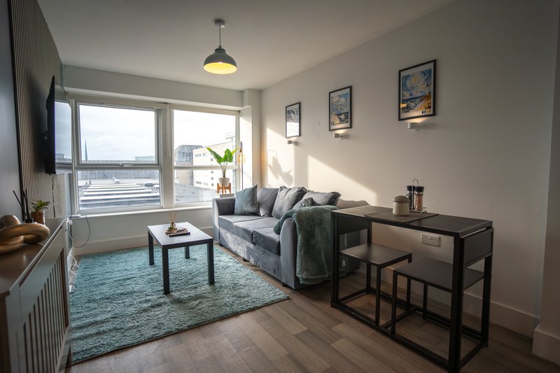 Bright living room with sofa, coffee table, desk, large windows overlooking water