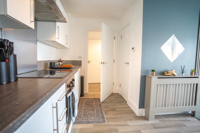 Modern galley kitchen with dark countertops, white cabinets and stainless steel appliances