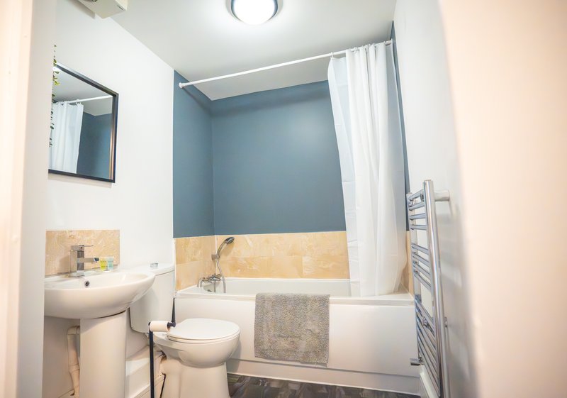 Modern bathroom with white sink, toilet, bathtub, mirror and towel rail