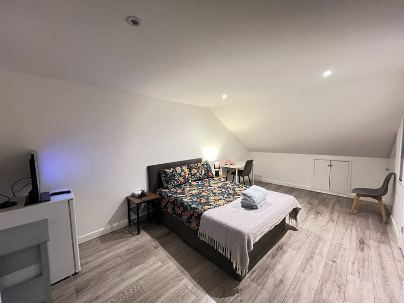 Attic bedroom with double bed, patterned duvet, wooden flooring and sloped ceiling
