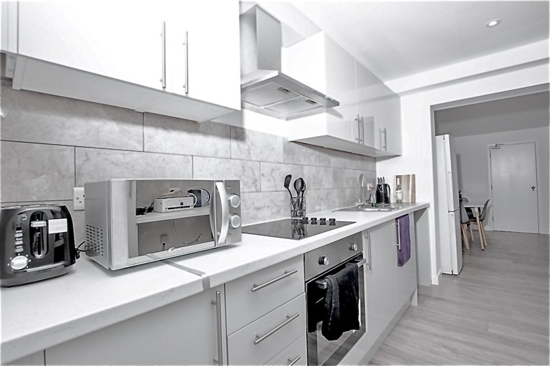 Modern kitchen with white cabinetry, grey tile backsplash, stainless steel appliances and countertop