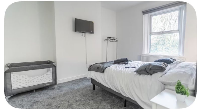 Bright bedroom with double bed, TV wall mount, cot, window and potted plant