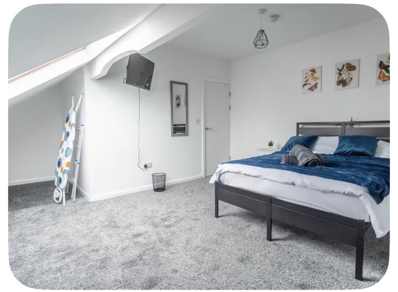 Attic bedroom with double bed, blue bedding, grey carpet and sloped ceiling