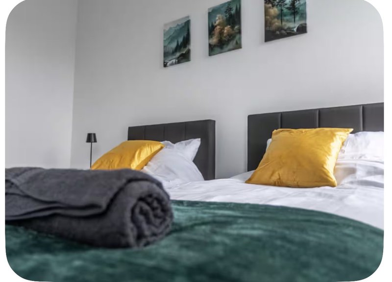 Modern bedroom with double bed, yellow pillows, dark headboard and landscape wall art