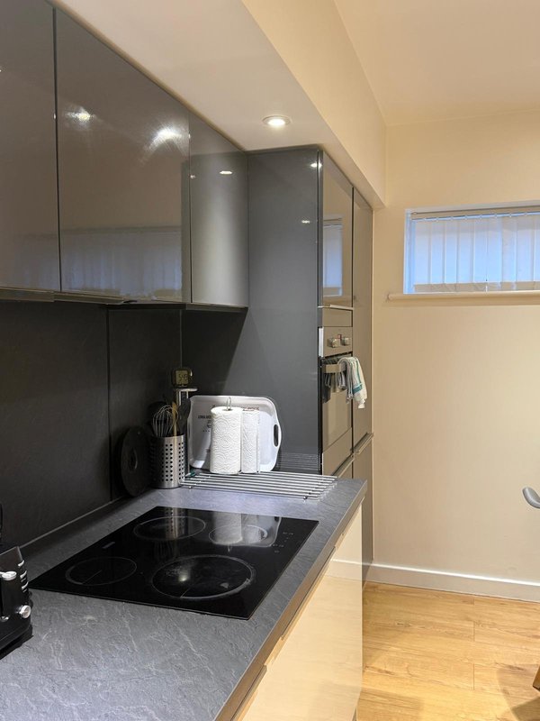 Modern kitchen with black cabinetry, gray countertop, induction hob and stainless steel appliances