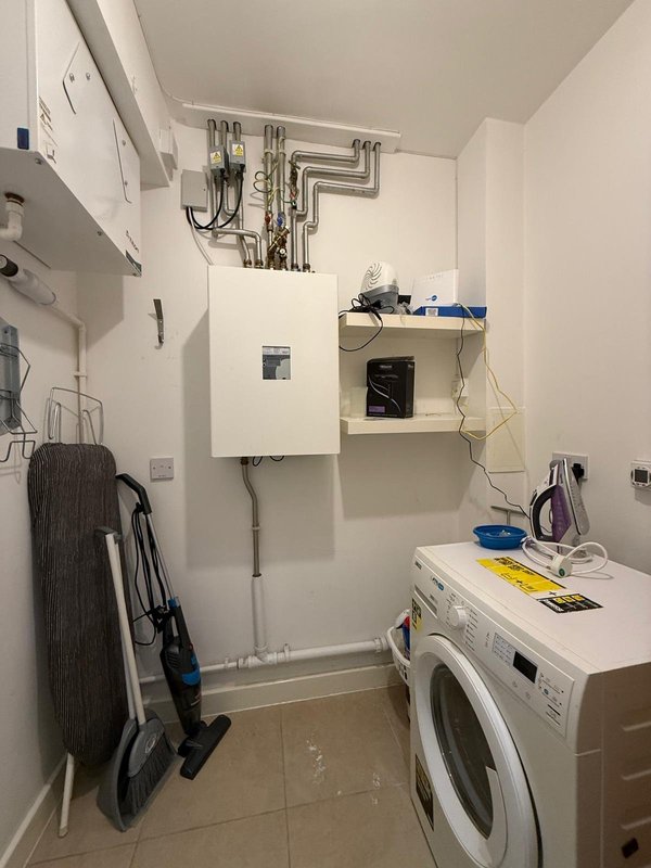 Utility room with washing machine, wall-mounted boiler, shelving and storage items